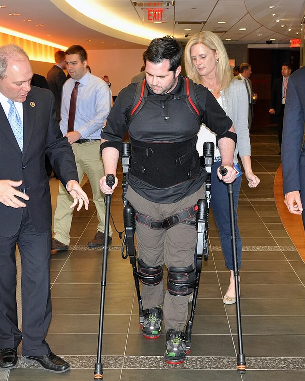 A veteran walking with an Indego exoskeleton between parallel bars.